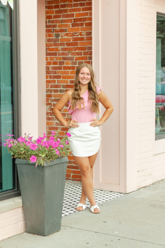 senior girl posing by a storefront in downtown port huron for her senior photos